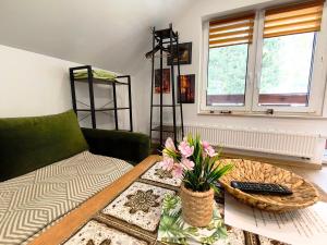 a living room with a couch and a table with flowers on it at Gajówka Świt in Łyskowo
