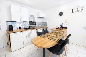 a kitchen with a wooden table and black chairs at La Perle de la Baie - Plages à pied & Hyper centre in Pornichet