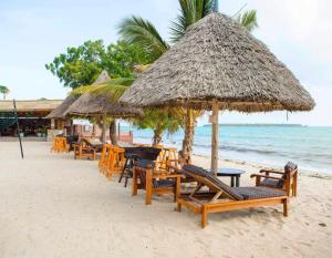 a beach with tables and chairs and a straw umbrella at Kijiji Beach Resort in Dar es Salaam