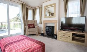 a bedroom with a flat screen tv and a fireplace at Bude Holiday Resort by Away Resorts in Bude