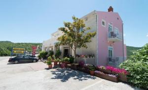 a pink house with flowers in a parking lot at Hotel Villa Matić in Neum