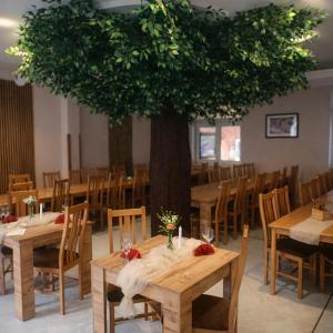 a dining room with wooden tables and a tree at Horský Hotel Magura in Chvojnica