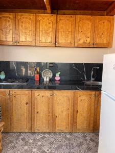 a kitchen with wooden cabinets and a white refrigerator at Chez Manon & Said in Tamraght Ouzdar