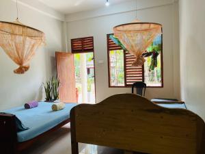 a bedroom with a bed and two windows at Ranathunga Guest Kataragama in Kataragama