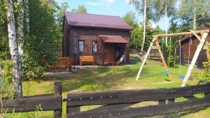 a log cabin with a swing and a playground at Domki nad Wałpuszem in Stare Kiejkuty