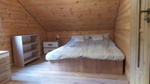 a bedroom with a bed in a wooden cabin at Domki nad Wałpuszem in Stare Kiejkuty