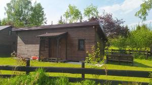 a small wooden cabin with a bench in a yard at Domki nad Wałpuszem in Stare Kiejkuty