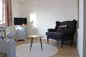 a living room with a chair and a table at Flair-Hotel Neeth in Lehmkuhlen