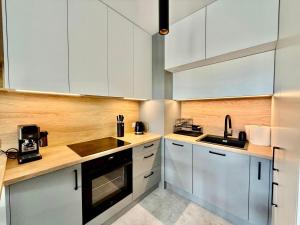a kitchen with white cabinets and a sink at Jarzebinowa Loft by JumpInHere in Nowy Dwór Mazowiecki +4 photos