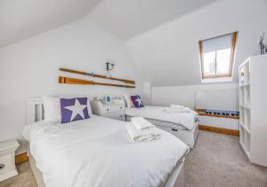two beds in a room with white walls at Charming Family Stables Conversion - Pass the Keys in Emsworth