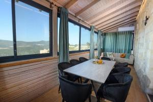 a table and chairs in a room with large windows at Even Vanof - אבן ונוף in Safed +17 photos