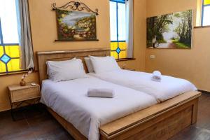 two beds in a room with two windows at Even Vanof - אבן ונוף in Safed