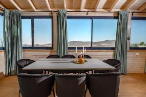a dining room with a table and chairs and windows at Even Vanof - אבן ונוף in Safed