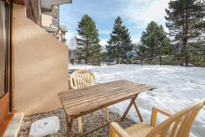 a wooden table and chairs on a patio with snow at Le Martagon - Proche Station de Ski in Gresse-en-Vercors +10 photos