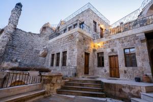 an old stone building with stairs in front of it at Temenni Evi Cave Hotel in Ürgüp