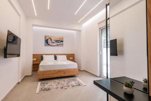 a white bedroom with a bed and a desk at Vila Amare in Sarandë