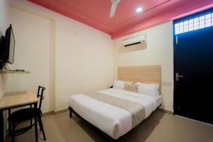 a bedroom with a bed and a desk and a door at Capitol Square Near Railway Station in Jaipur