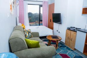 a living room with a couch and a television and a bed at comfystdkiambu in Kiambu