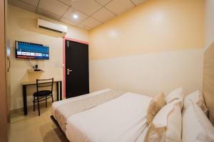 a bedroom with a bed and a desk and a tv at Capitol Square Near Railway Station in Jaipur +31 photos