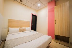 a bedroom with a white bed and a red wall at Capitol Square Near Railway Station in Jaipur