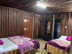 two beds in a room with wooden walls at Manjosila Homestay in Mirik +4 photos