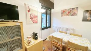 a living room with a table and a television and a dining room at Baradello Apartment & Flat by ca-Sa Check in Le Bratte