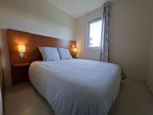 a bedroom with a large white bed with a window at cottage poussin 12 picine lave linge in Chaveignes +23 photos