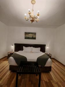 a bedroom with a large bed and a chandelier at Afma Nueva Alta in Cusco