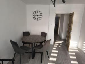 a table and chairs in a room with a clock on the wall at Apartament w Biłgoraju in Biłgoraj