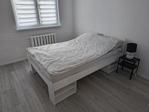 a white bed in a room with a chair and a window at Apartament w Biłgoraju in Biłgoraj