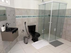 a bathroom with a glass shower and a black toilet at Sweet home in São Luís