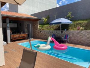 a swimming pool with two inflatable flamingos and an umbrella at Casa com Piscina em Jarinu in Jarinu