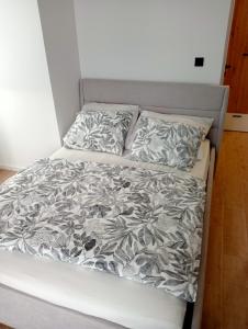 a bed with a gray and white comforter and pillows at Apartament 37 in Sosnowiec