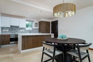 a kitchen with a black table and chairs and a chandelier at Ruby - 2-bed condo with pool in Saint Georgeʼs