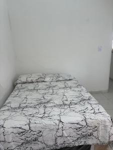 a bed in a white room with a wrinkled sheet at Sweet home in São Luís