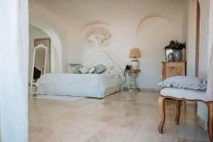 a white bedroom with a bed and a mirror at Hotel Pulicinu in Baja Sardinia