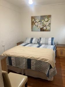 a bedroom with a bed and a painting on the wall at Hostal Colonial in Iquique