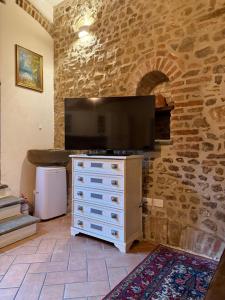 a living room with a television on a stone wall at Dimora dei cesari in Città di Castello