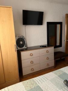 a bedroom with a dresser with a television on the wall at Hostal Colonial in Iquique
