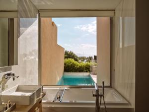 a bathroom with a tub and a window with a swimming pool at Eagles Villas - Small Luxury Hotels of The World in Ouranoupoli +85 photos