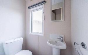 a bathroom with a toilet and a sink and a window at Chalet am Wattenmeer Holland in Lauwersoog +8 photos