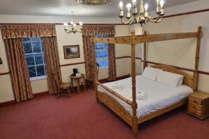 a bedroom with a four poster bed and a table at The Miners Rest, formerly The Radstock Hotel, near Bath in Radstock