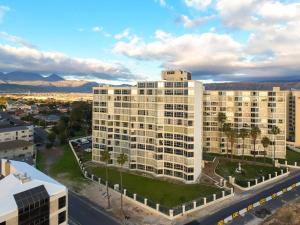 an aerial view of a large white building with palm trees at Coastal Condo Strand in Strand