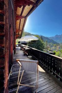 a chair sitting on a deck with an umbrella at Apartment Steirösli 1- & 2- Stock by Interhome in Lenk