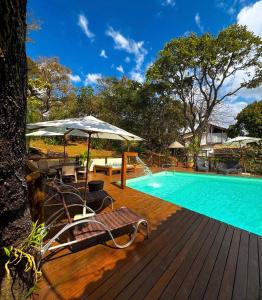 a pool with chairs and an umbrella on a wooden deck at Pousada Santa Vila in Serra do Cipo
