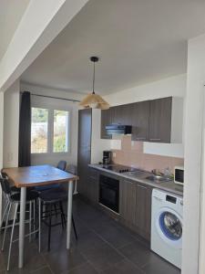 a kitchen with a table and a washer and dryer at maison être mer et montagne in Ponte-Leccia