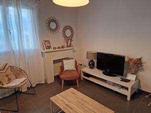 a living room with a flat screen tv and a chair at maison être mer et montagne in Ponte-Leccia