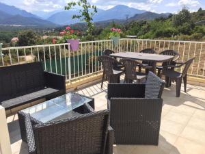 a patio with tables and chairs with mountains in the background at maison être mer et montagne in Ponte-Leccia