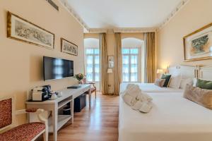 a hotel room with two beds and a desk at Casa Romana Hotel Boutique in Seville
