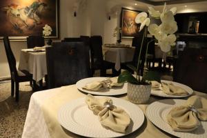 a dining room with white plates and flowers on a table at Hotel Inambu Villavicencio in Villavicencio